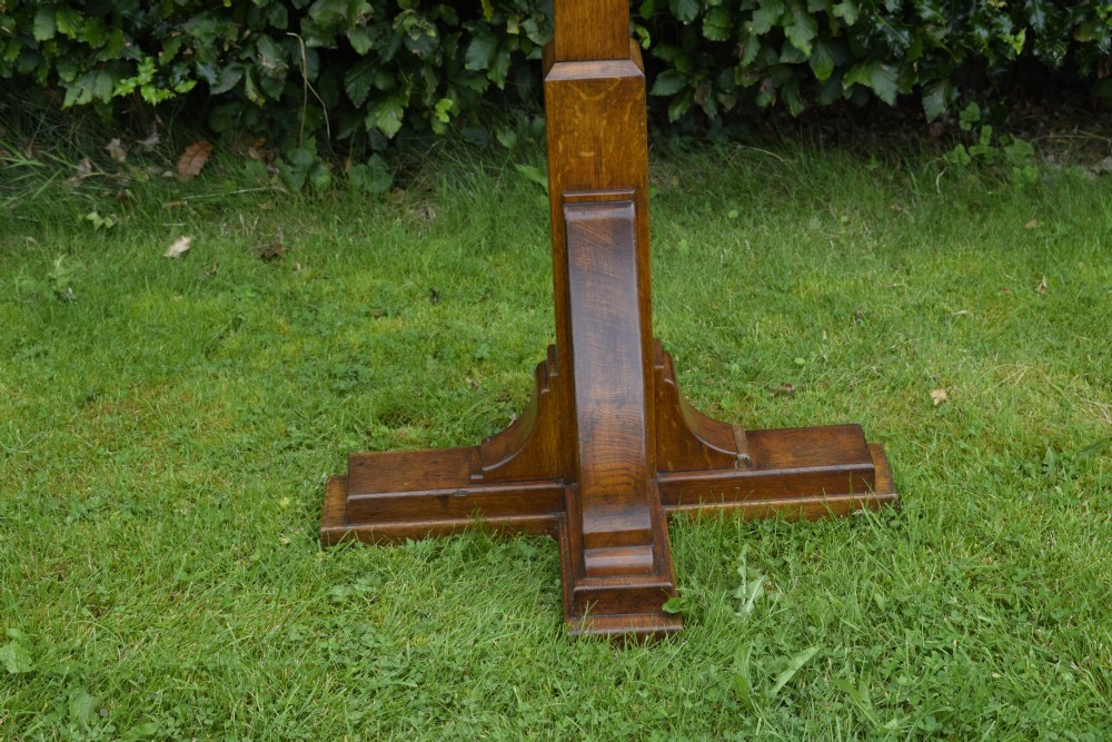 An early 20th-century solid oak floor-standing lectern featuring an angled book rest above a central column supported by a stepped cruciform base. View XVII