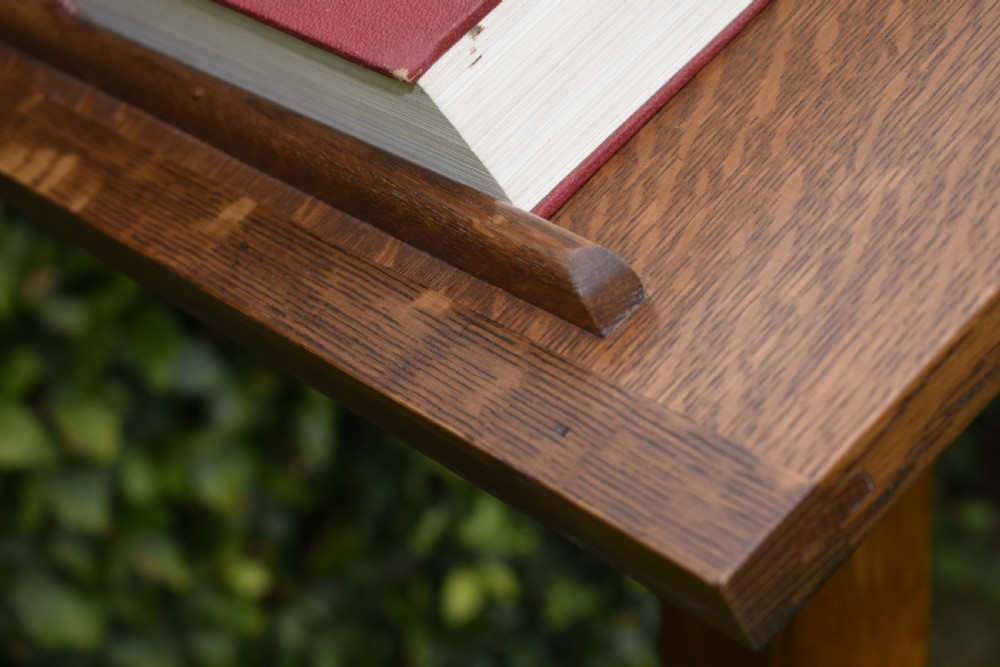 An early 20th-century solid oak floor-standing lectern featuring an angled book rest above a central column supported by a stepped cruciform base. View XX