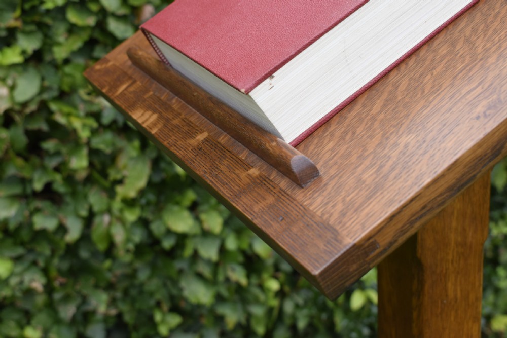 An early 20th-century solid oak floor-standing lectern featuring an angled book rest above a central column supported by a stepped cruciform base. View XXI