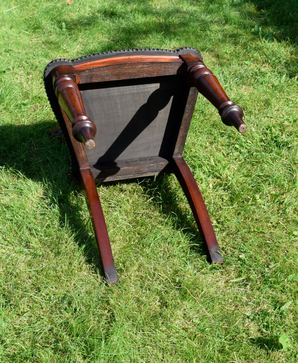A Victorian mahogany hall chair with a carved shield-shaped backrest, stud-trimmed dark seat, turned front legs, and splayed rear legs. View XVI