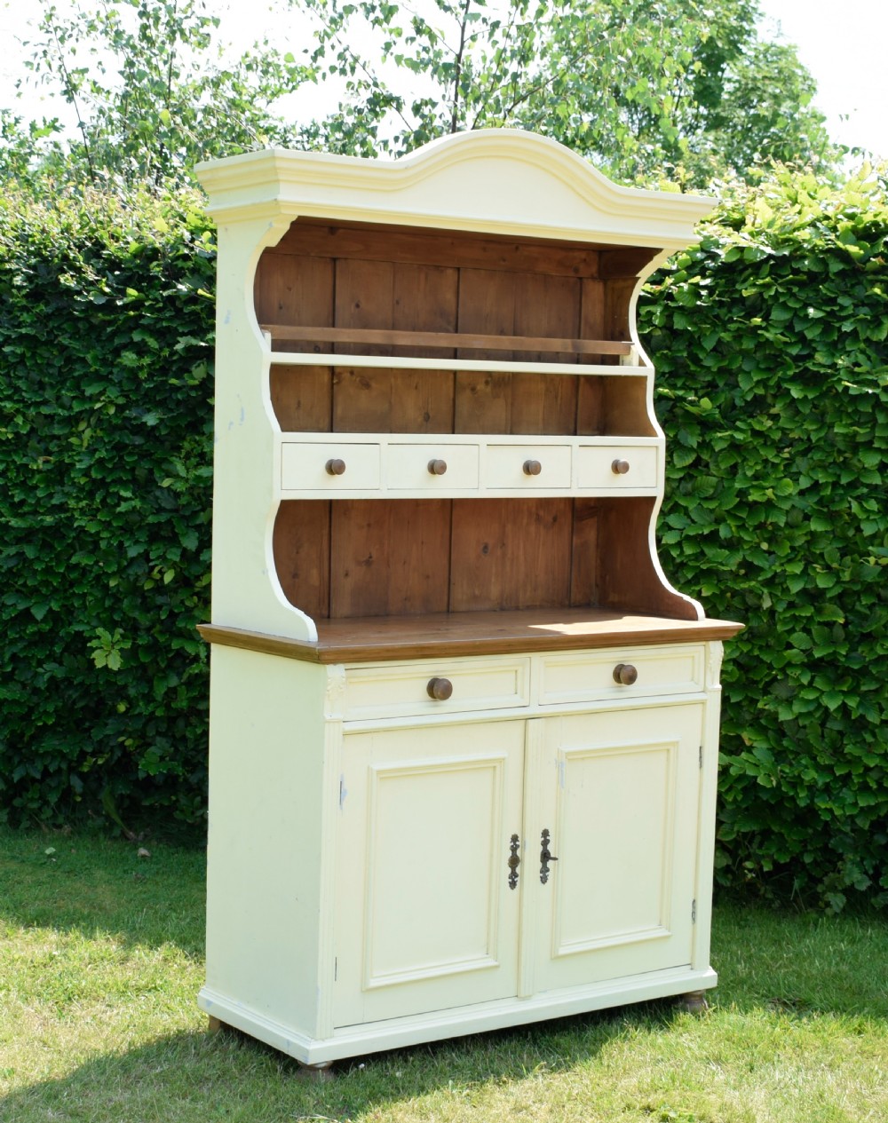 An early twentieth-century painted cream pine kitchen dresser featuring an upper shelf rack with small drawers over a two-door base cupboard. View III