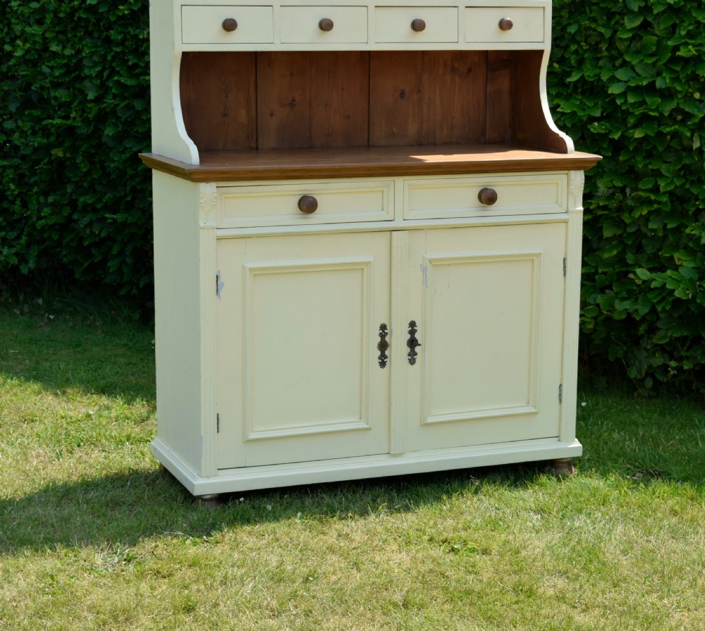 An early twentieth-century painted cream pine kitchen dresser featuring an upper shelf rack with small drawers over a two-door base cupboard. View VII