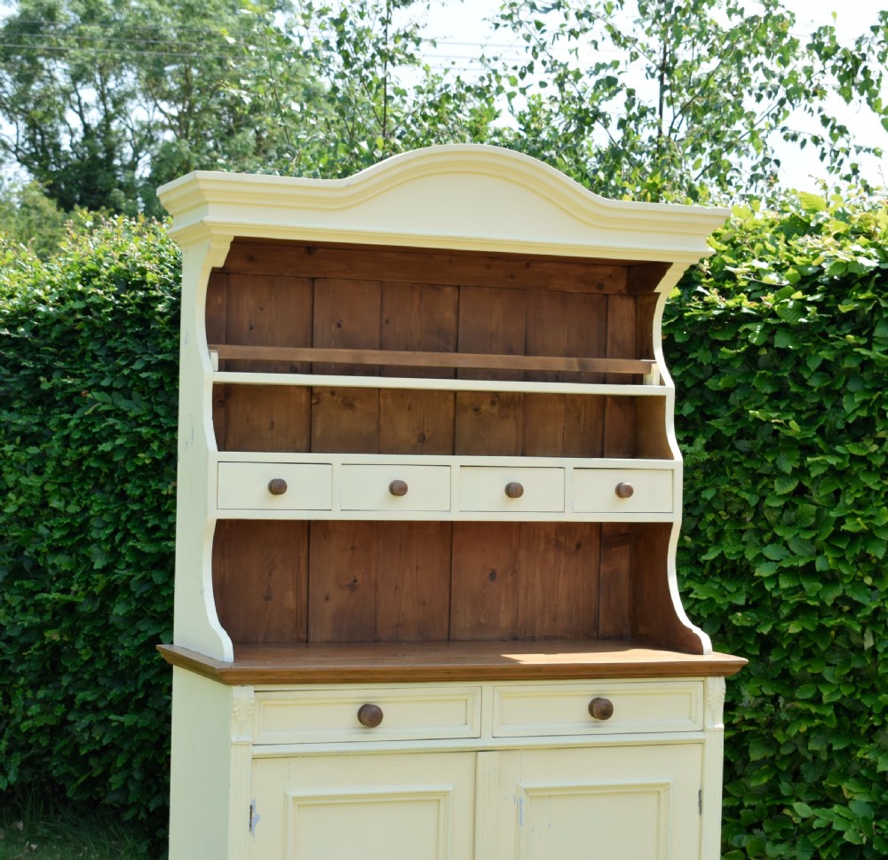 An early twentieth-century painted cream pine kitchen dresser featuring an upper shelf rack with small drawers over a two-door base cupboard. View VIII