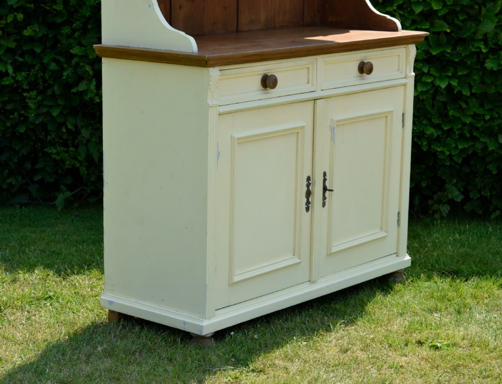 An early twentieth-century painted cream pine kitchen dresser featuring an upper shelf rack with small drawers over a two-door base cupboard. View XI