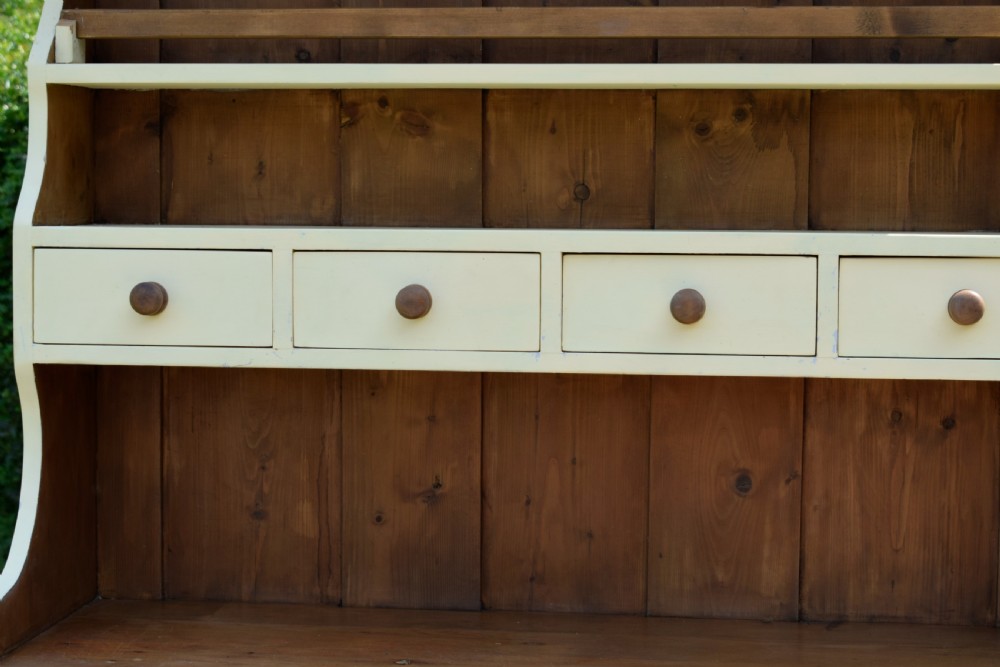 An early twentieth-century painted cream pine kitchen dresser featuring an upper shelf rack with small drawers over a two-door base cupboard. View XII