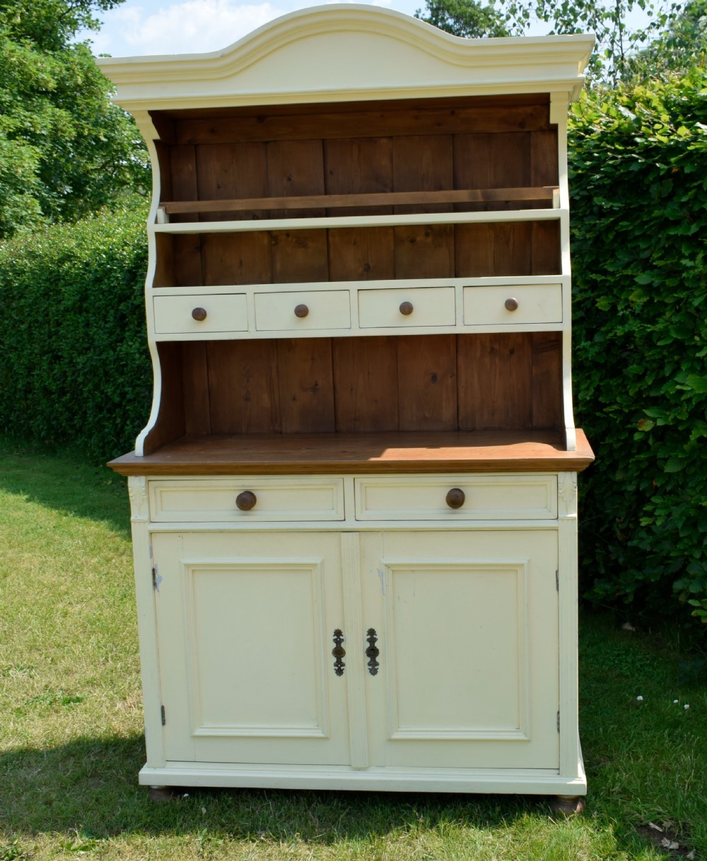 An early twentieth-century painted cream pine kitchen dresser featuring an upper shelf rack with small drawers over a two-door base cupboard. View XIII