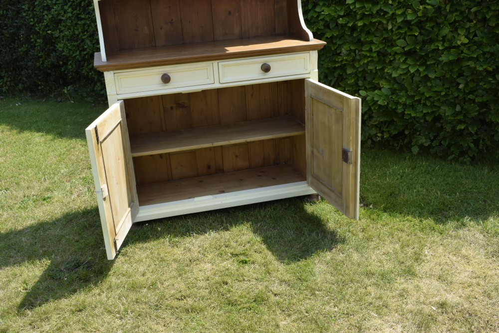 An early twentieth-century painted cream pine kitchen dresser featuring an upper shelf rack with small drawers over a two-door base cupboard. View XVI