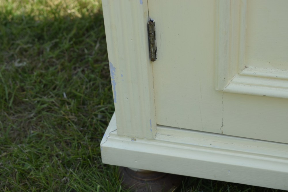 An early twentieth-century painted cream pine kitchen dresser featuring an upper shelf rack with small drawers over a two-door base cupboard. View XVIII