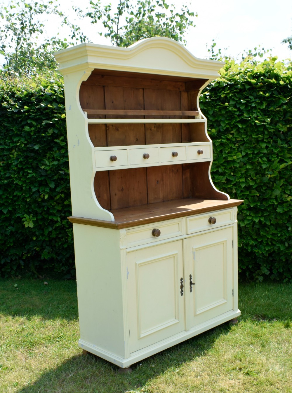 An early twentieth-century painted cream pine kitchen dresser featuring an upper shelf rack with small drawers over a two-door base cupboard. View XXI
