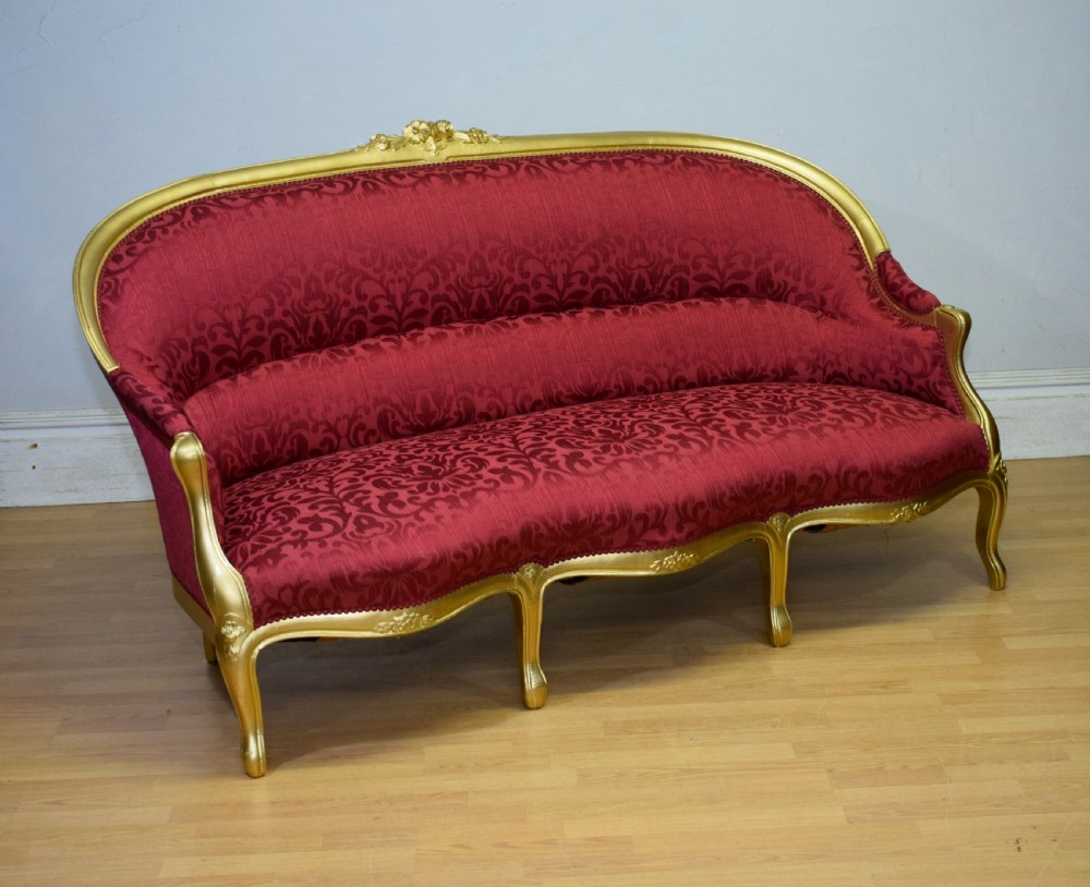 An antique French canape settee with a carved gold-gilded frame, cabriole legs, and red patterned damask upholstery. View II