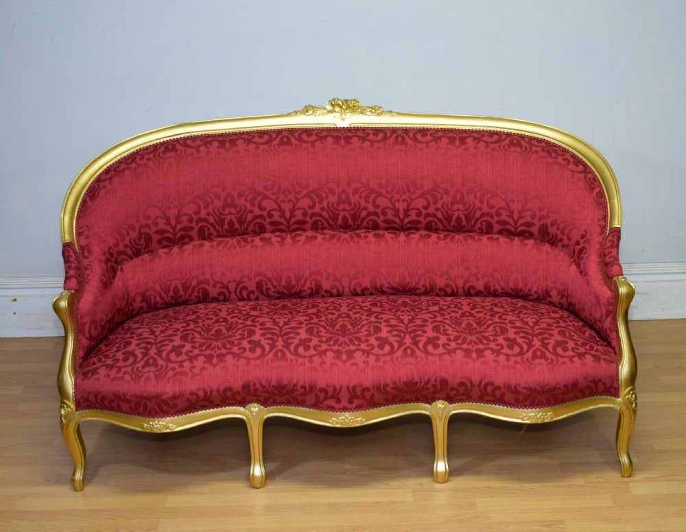 An antique French canape settee with a carved gold-gilded frame, cabriole legs, and red patterned damask upholstery. View III