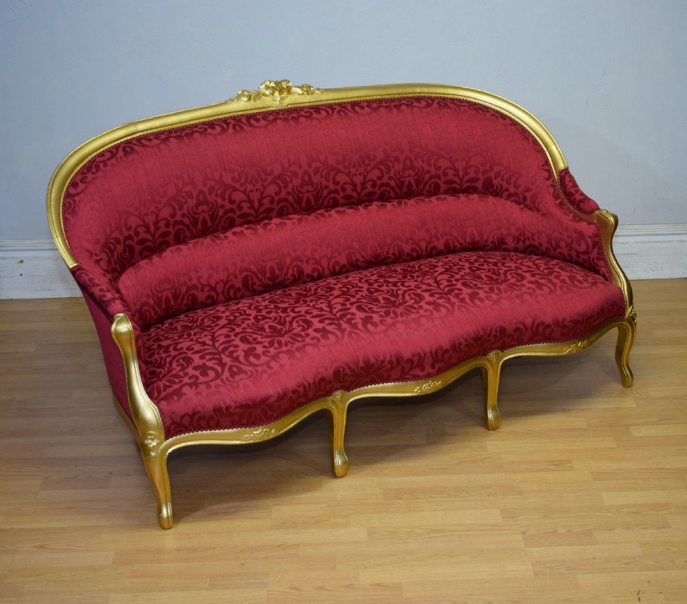 An antique French canape settee with a carved gold-gilded frame, cabriole legs, and red patterned damask upholstery. View XIII