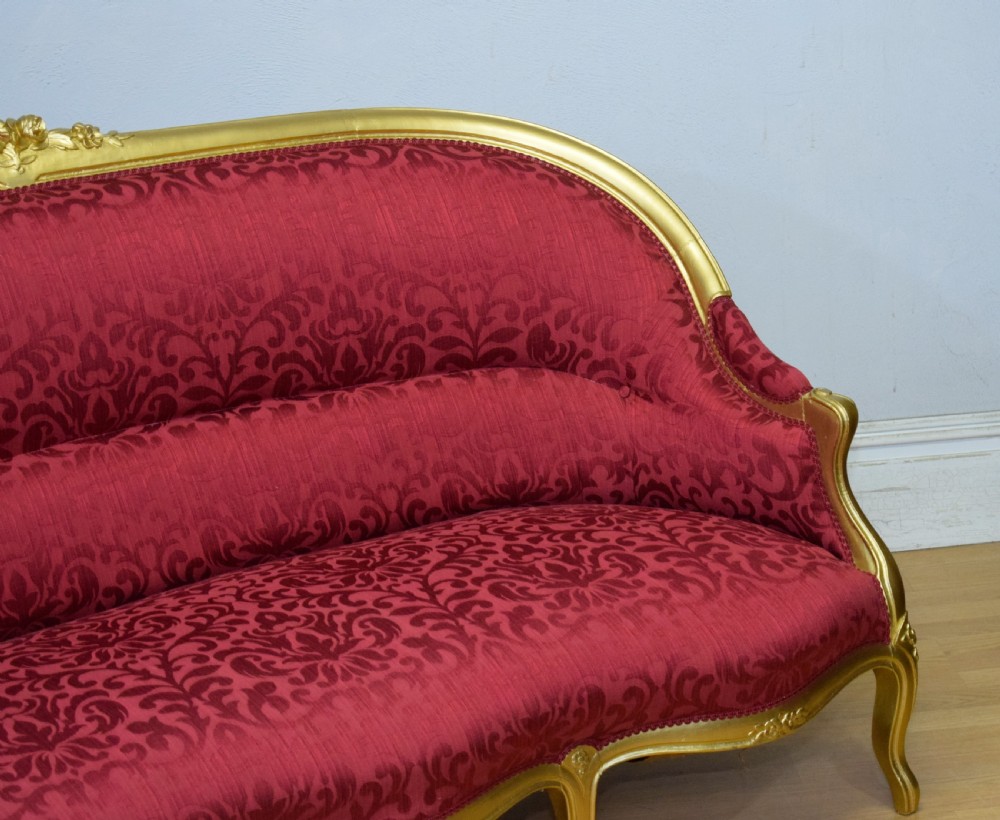 An antique French canape settee with a carved gold-gilded frame, cabriole legs, and red patterned damask upholstery. View XV