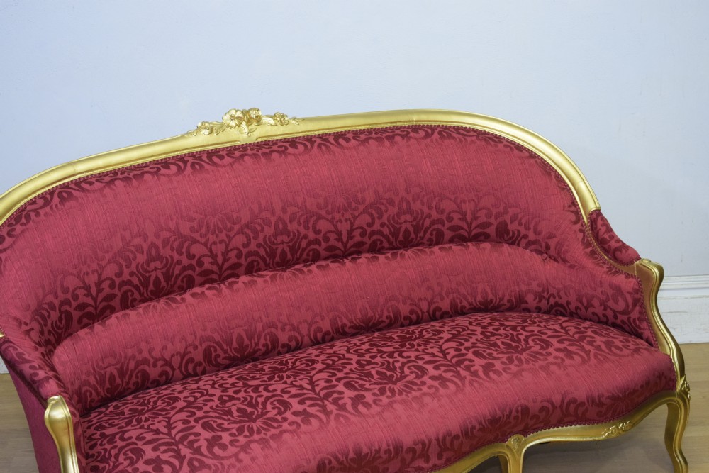 An antique French canape settee with a carved gold-gilded frame, cabriole legs, and red patterned damask upholstery. View XVI
