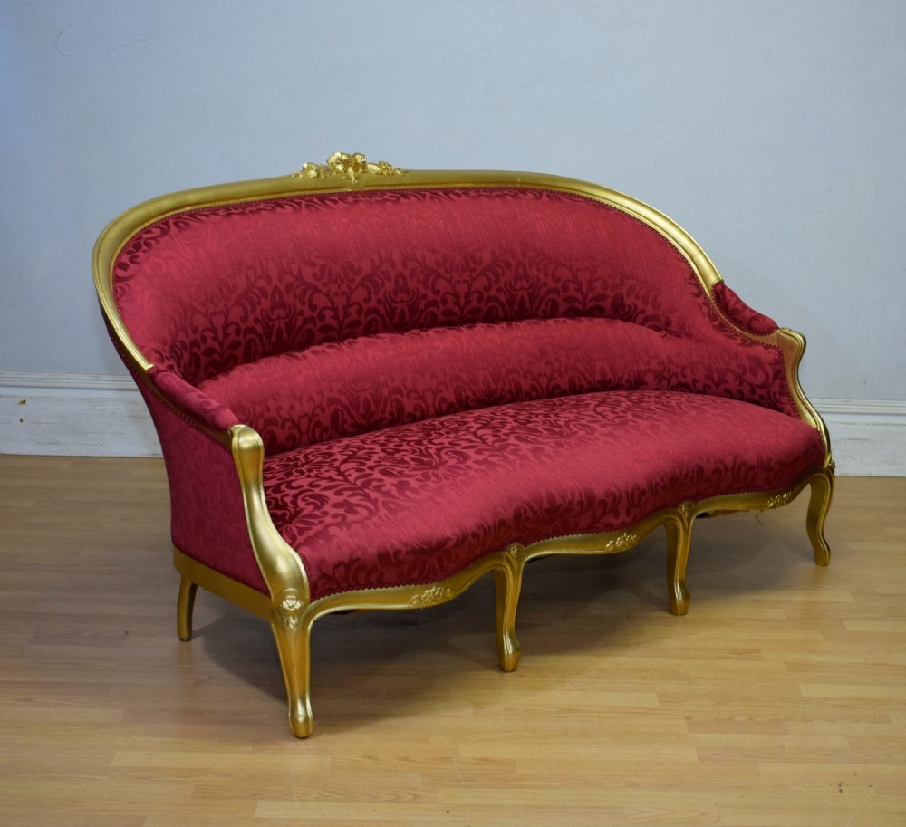 An antique French canape settee with a carved gold-gilded frame, cabriole legs, and red patterned damask upholstery. View XVII