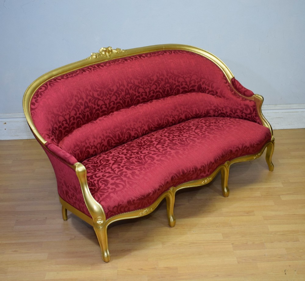 An antique French canape settee with a carved gold-gilded frame, cabriole legs, and red patterned damask upholstery. View XVIII