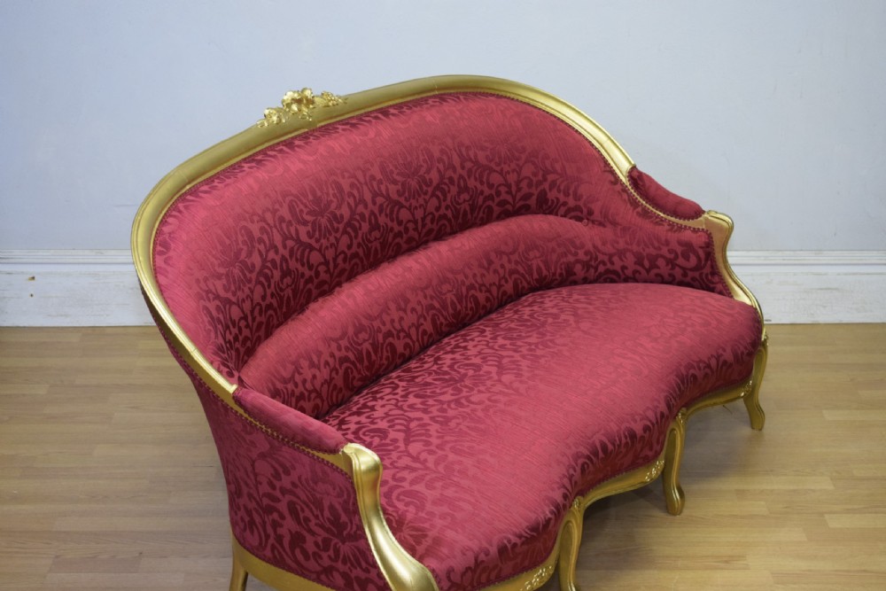An antique French canape settee with a carved gold-gilded frame, cabriole legs, and red patterned damask upholstery. View XXIV