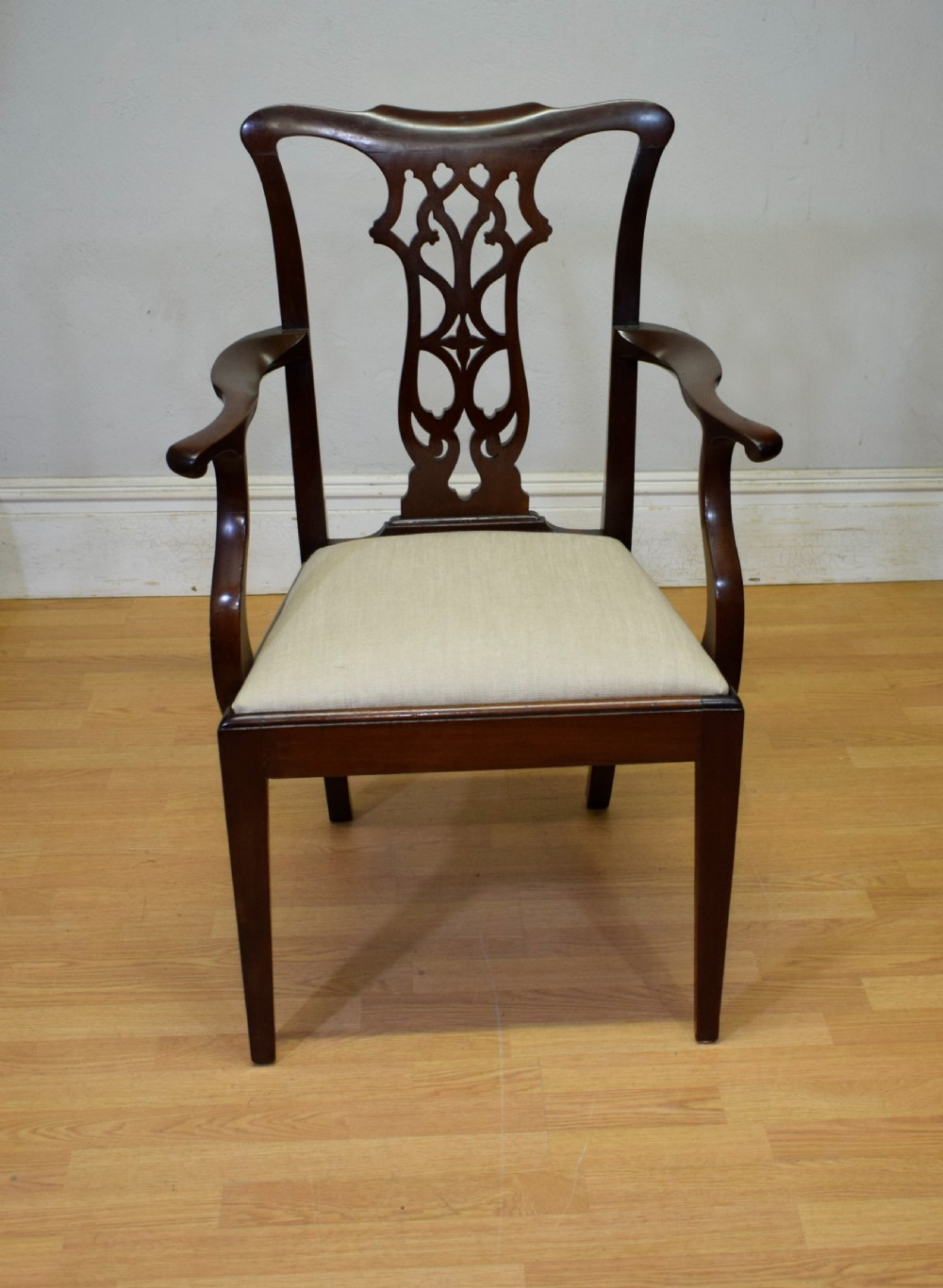 A 19th-century mahogany open armchair featuring a carved pierced back splat, curved arms, and a neutral cream upholstered seat. View IV