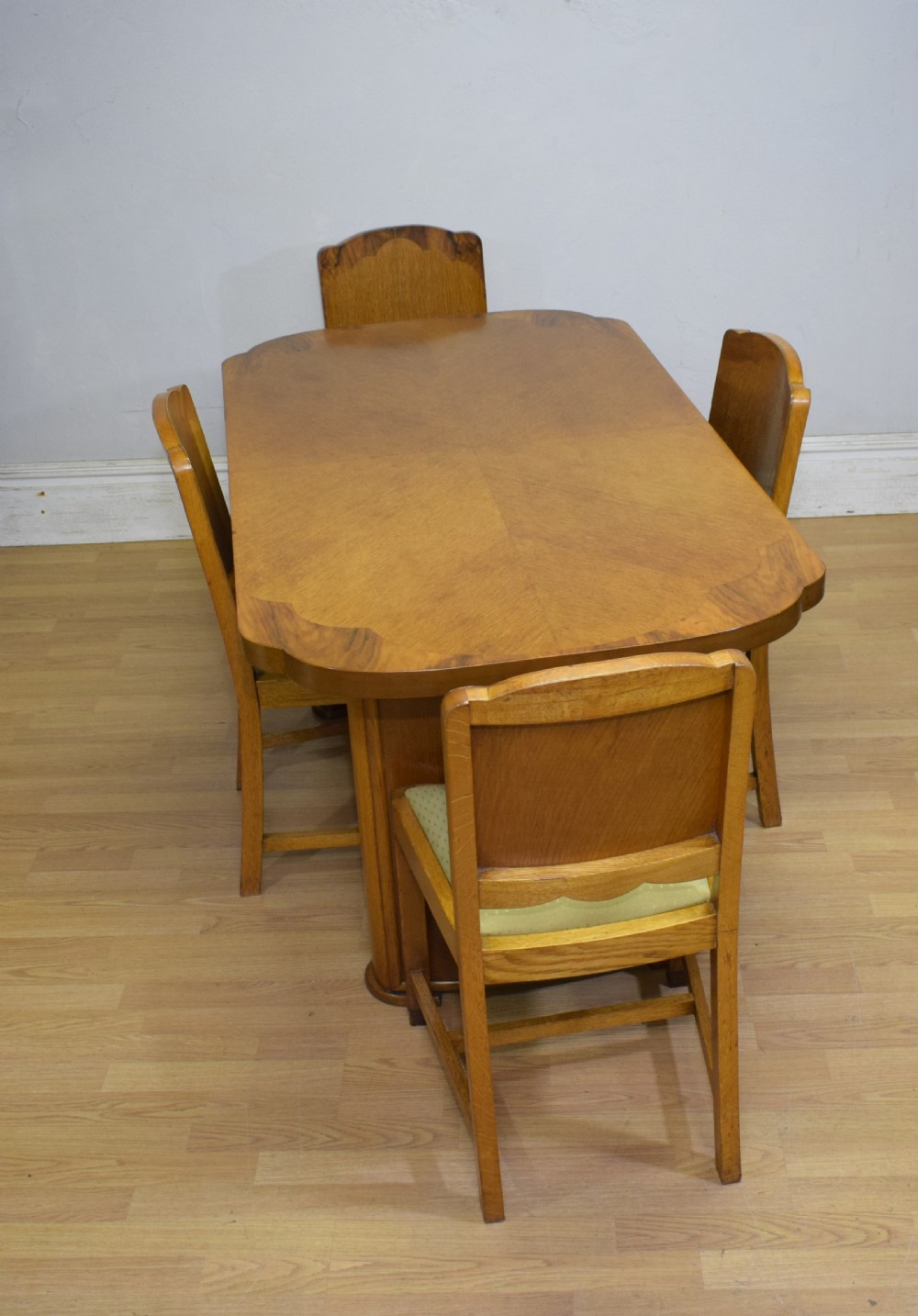 An Art Deco light oak dining suite featuring a shaped table with a central pedestal surrounded by four matching upholstered chairs. View II