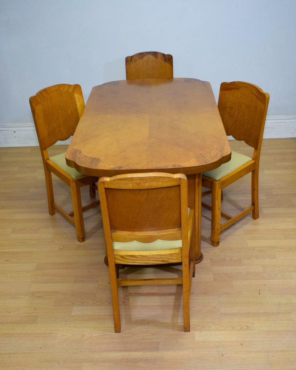 An Art Deco light oak dining suite featuring a shaped table with a central pedestal surrounded by four matching upholstered chairs. View III