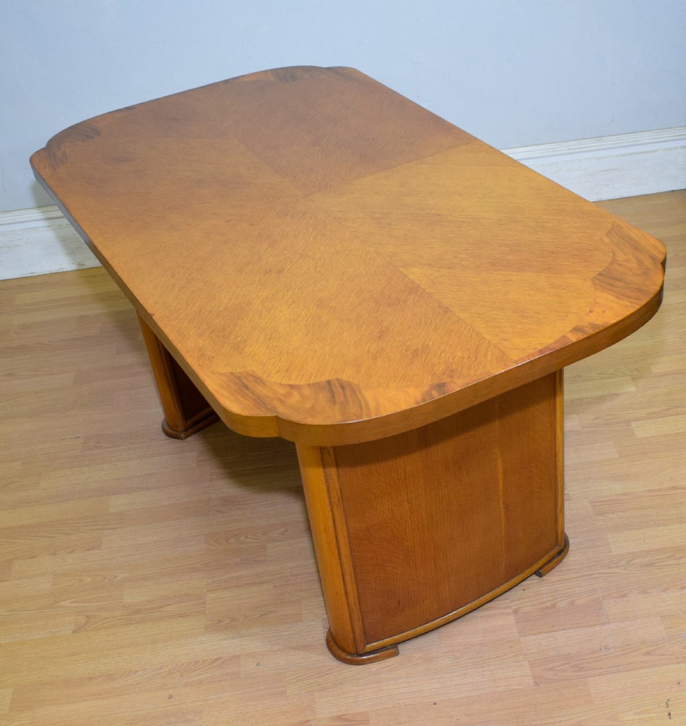An Art Deco light oak dining suite featuring a shaped table with a central pedestal surrounded by four matching upholstered chairs. View IV