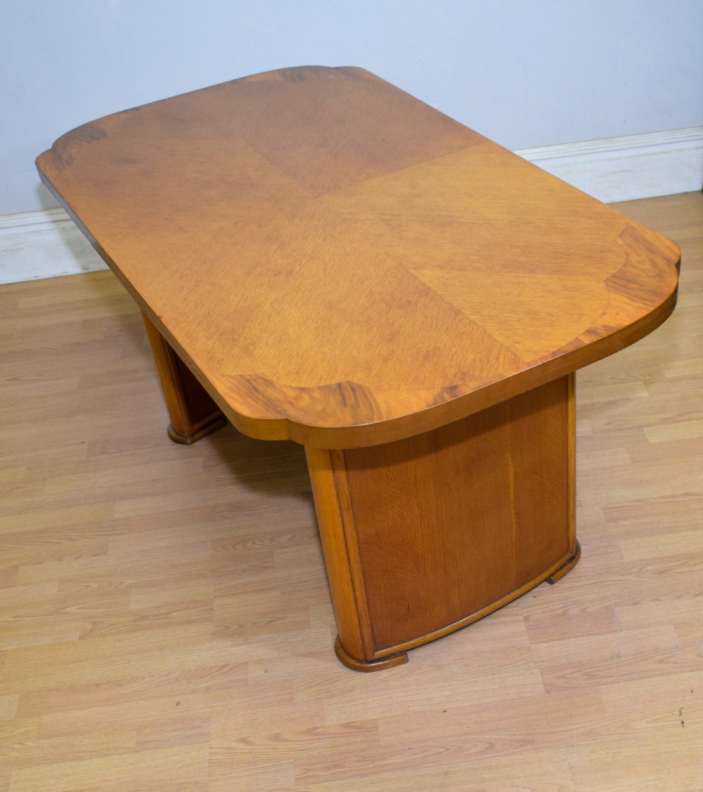 An Art Deco light oak dining suite featuring a shaped table with a central pedestal surrounded by four matching upholstered chairs. View VI