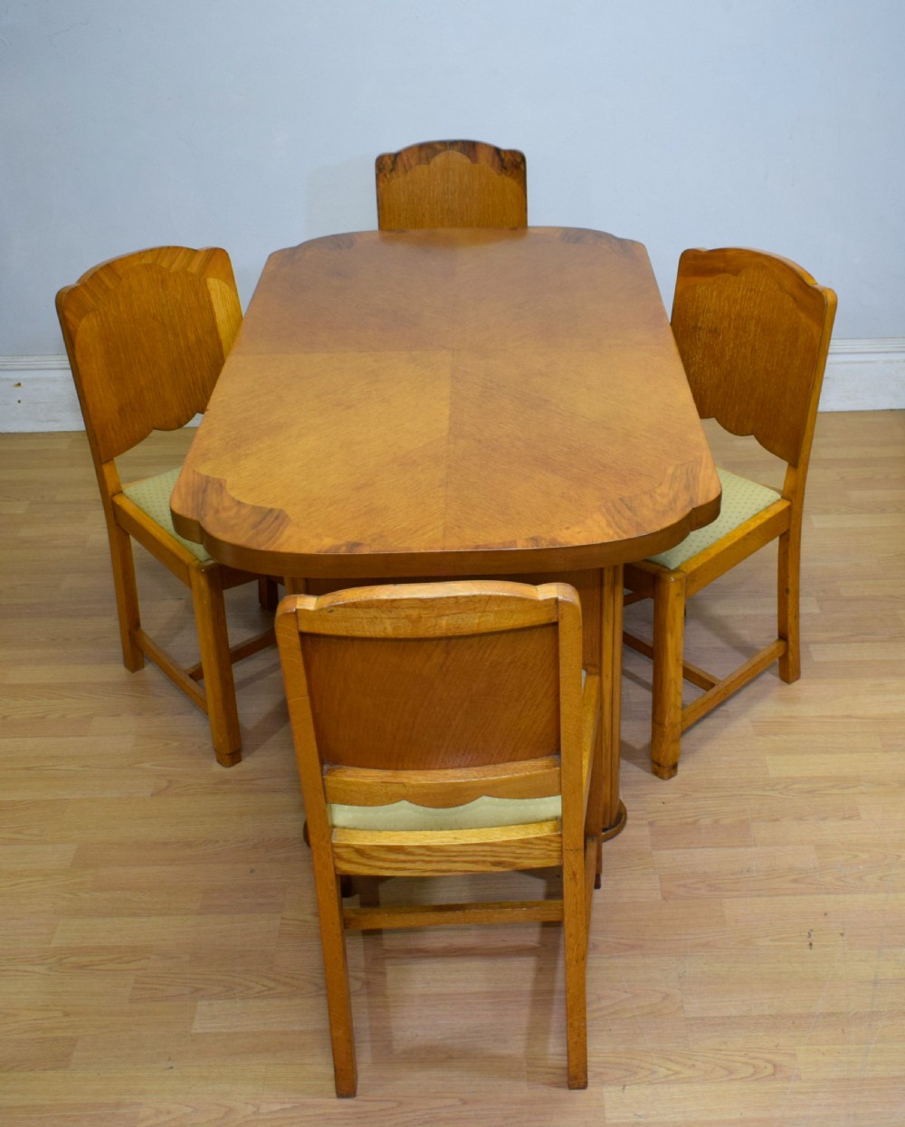An Art Deco light oak dining suite featuring a shaped table with a central pedestal surrounded by four matching upholstered chairs. View VII