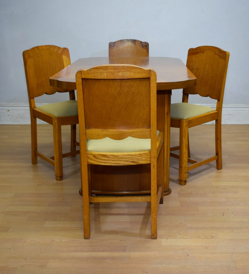 An Art Deco light oak dining suite featuring a shaped table with a central pedestal surrounded by four matching upholstered chairs. View VIII