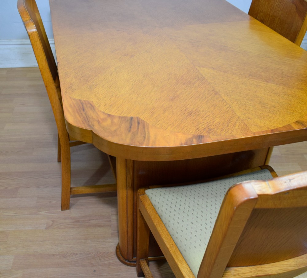 An Art Deco light oak dining suite featuring a shaped table with a central pedestal surrounded by four matching upholstered chairs. View XII