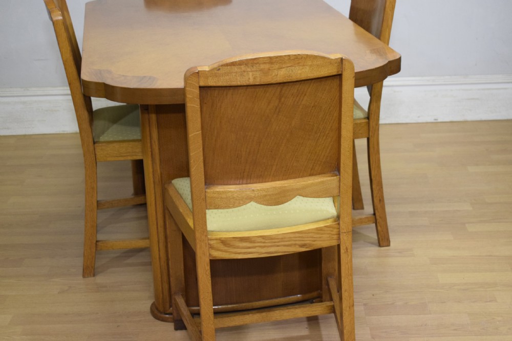 An Art Deco light oak dining suite featuring a shaped table with a central pedestal surrounded by four matching upholstered chairs. View XIV