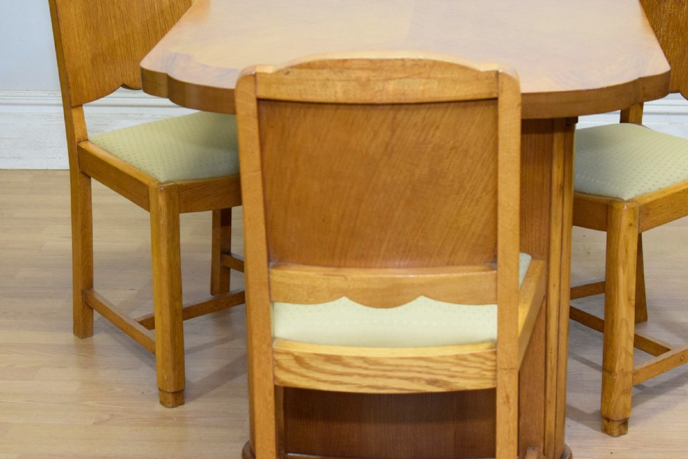 An Art Deco light oak dining suite featuring a shaped table with a central pedestal surrounded by four matching upholstered chairs. View XVII