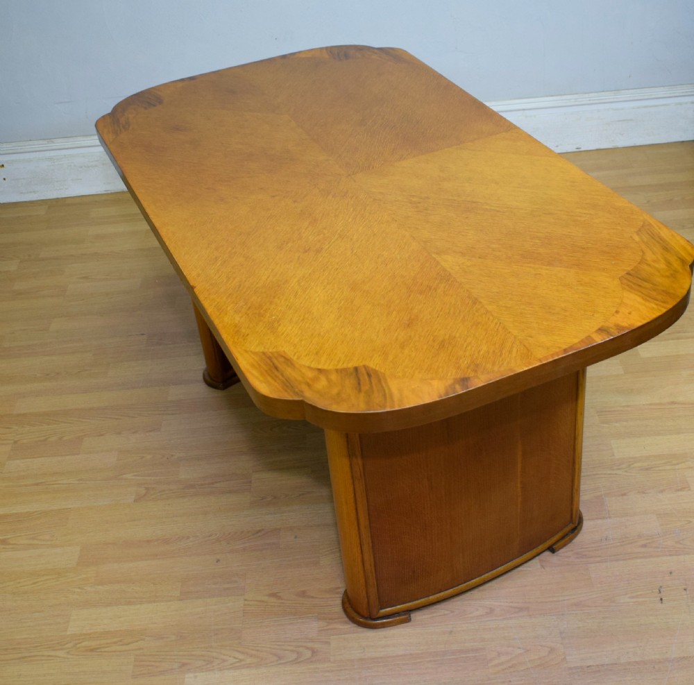 An Art Deco light oak dining suite featuring a shaped table with a central pedestal surrounded by four matching upholstered chairs. View XX