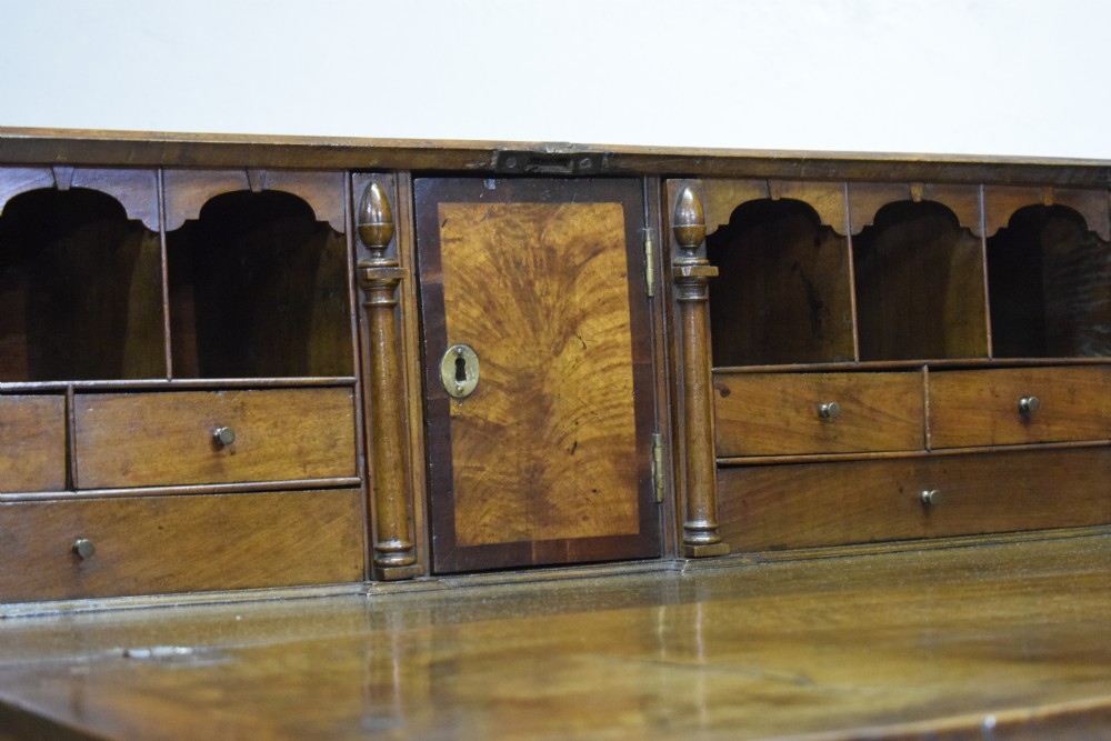 A Georgian walnut bureau featuring a sloped hinged front opening above four graduated drawers with decorative brass handles and bracket feet. View XIII