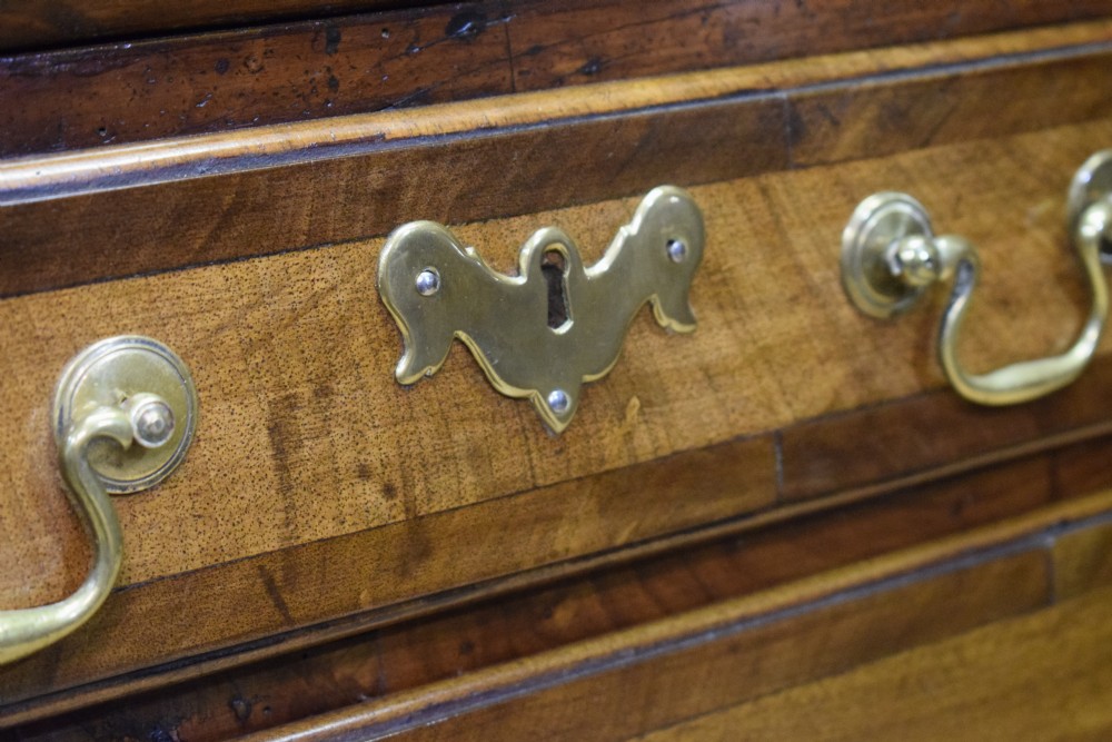 A Georgian walnut bureau featuring a sloped hinged front opening above four graduated drawers with decorative brass handles and bracket feet. View XV