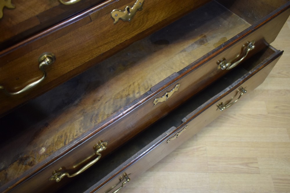 A Georgian walnut bureau featuring a sloped hinged front opening above four graduated drawers with decorative brass handles and bracket feet. View XVI