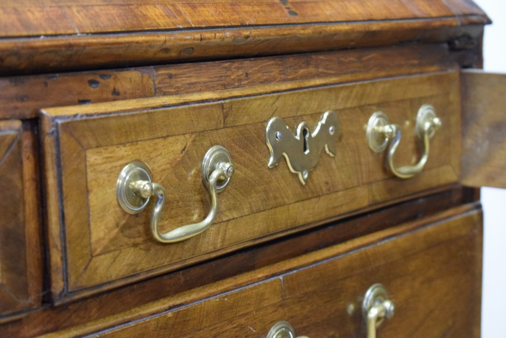 A Georgian walnut bureau featuring a sloped hinged front opening above four graduated drawers with decorative brass handles and bracket feet. View XXVII