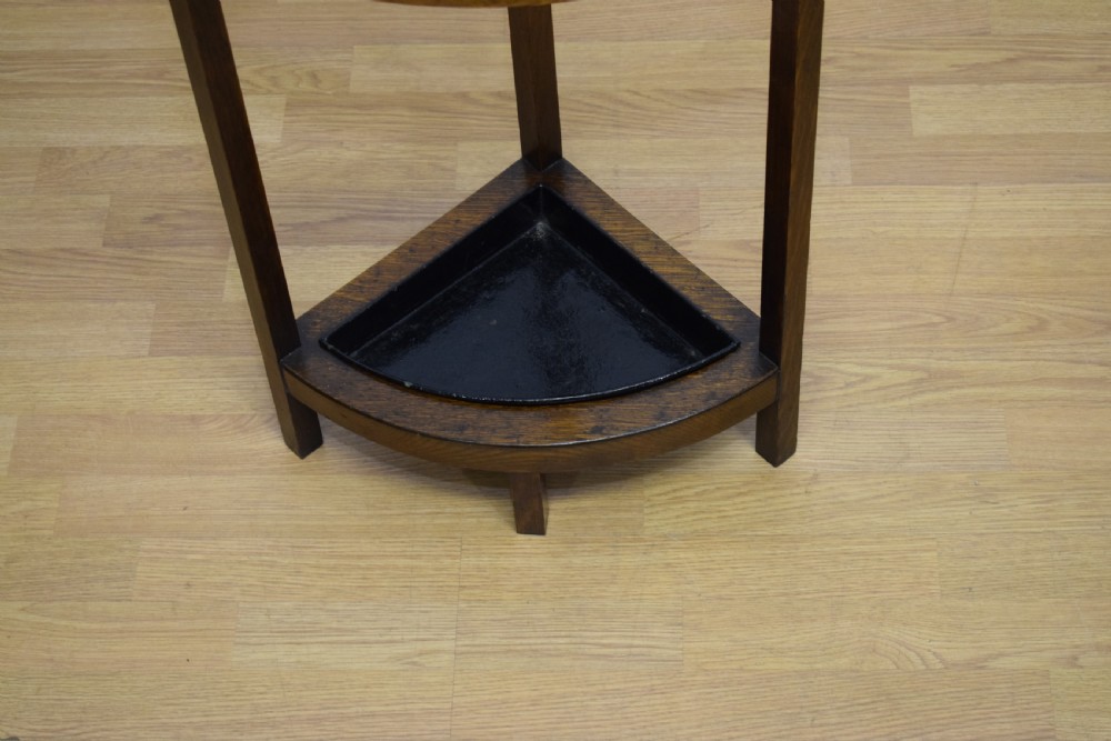 An Arts and Crafts dark oak corner stick stand featuring a curved upper front rail, straight vertical supports, and a black triangular metal drip tray. View VII