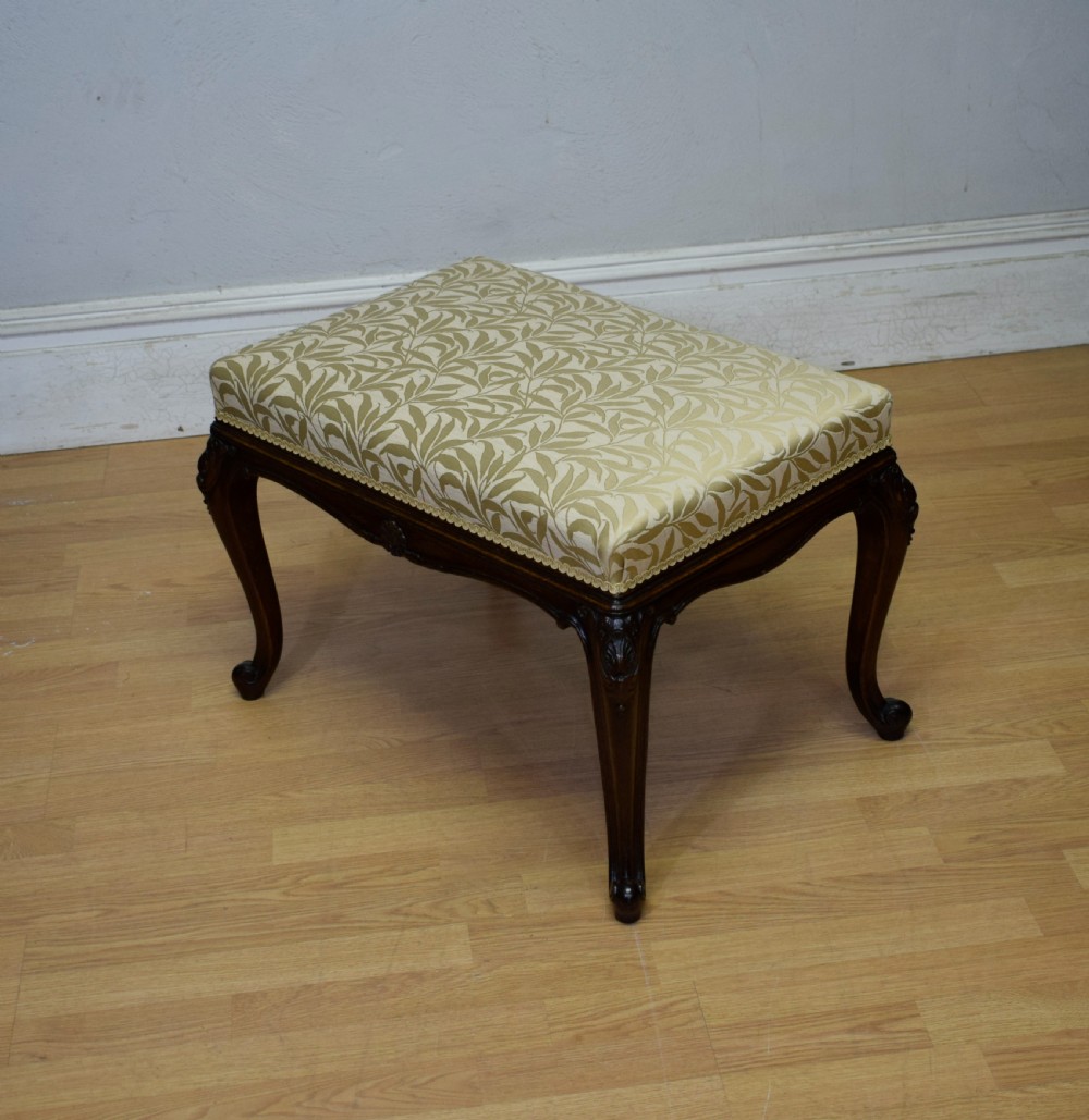 An early 20th-century French stool with carved dark timber cabriole legs and a cream and gold patterned fabric upholstered top. View III