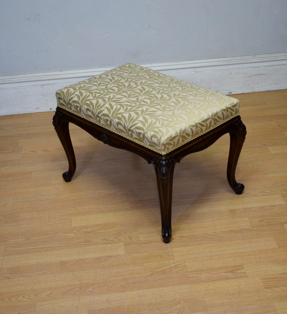 An early 20th-century French stool with carved dark timber cabriole legs and a cream and gold patterned fabric upholstered top. View VII