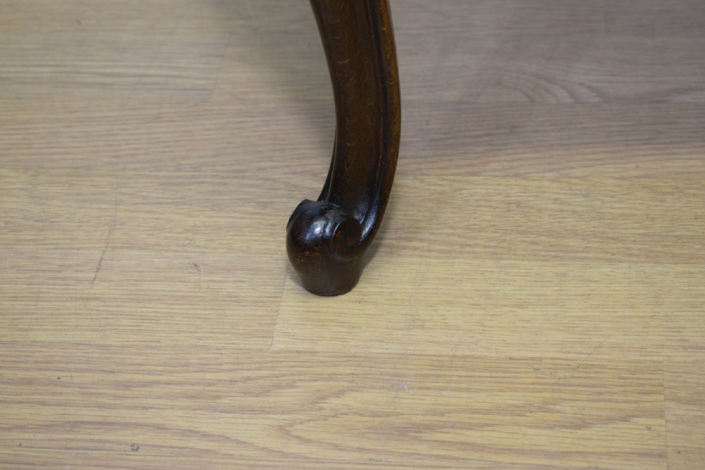 An early 20th-century French stool with carved dark timber cabriole legs and a cream and gold patterned fabric upholstered top. View XII