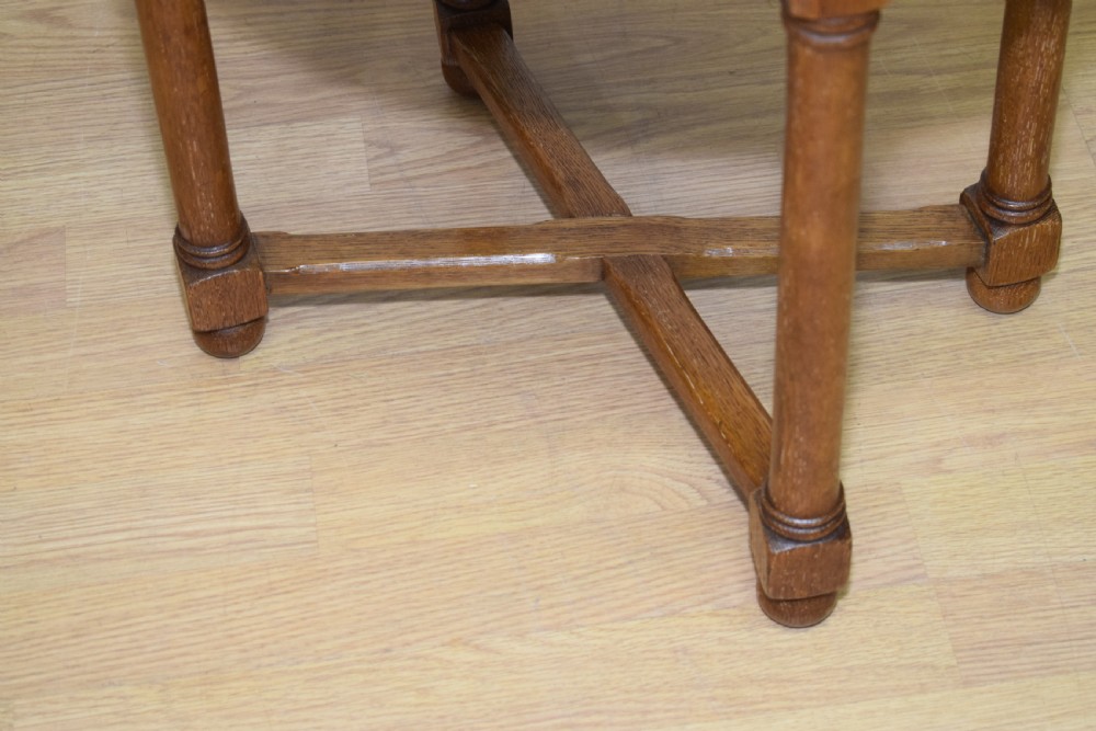 An antique Arts and Crafts oak stool featuring an oval red upholstered seat supported by four turned legs with a cross stretcher. View VII