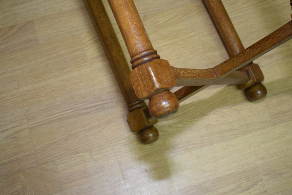 An antique Arts and Crafts oak stool featuring an oval red upholstered seat supported by four turned legs with a cross stretcher. View IX