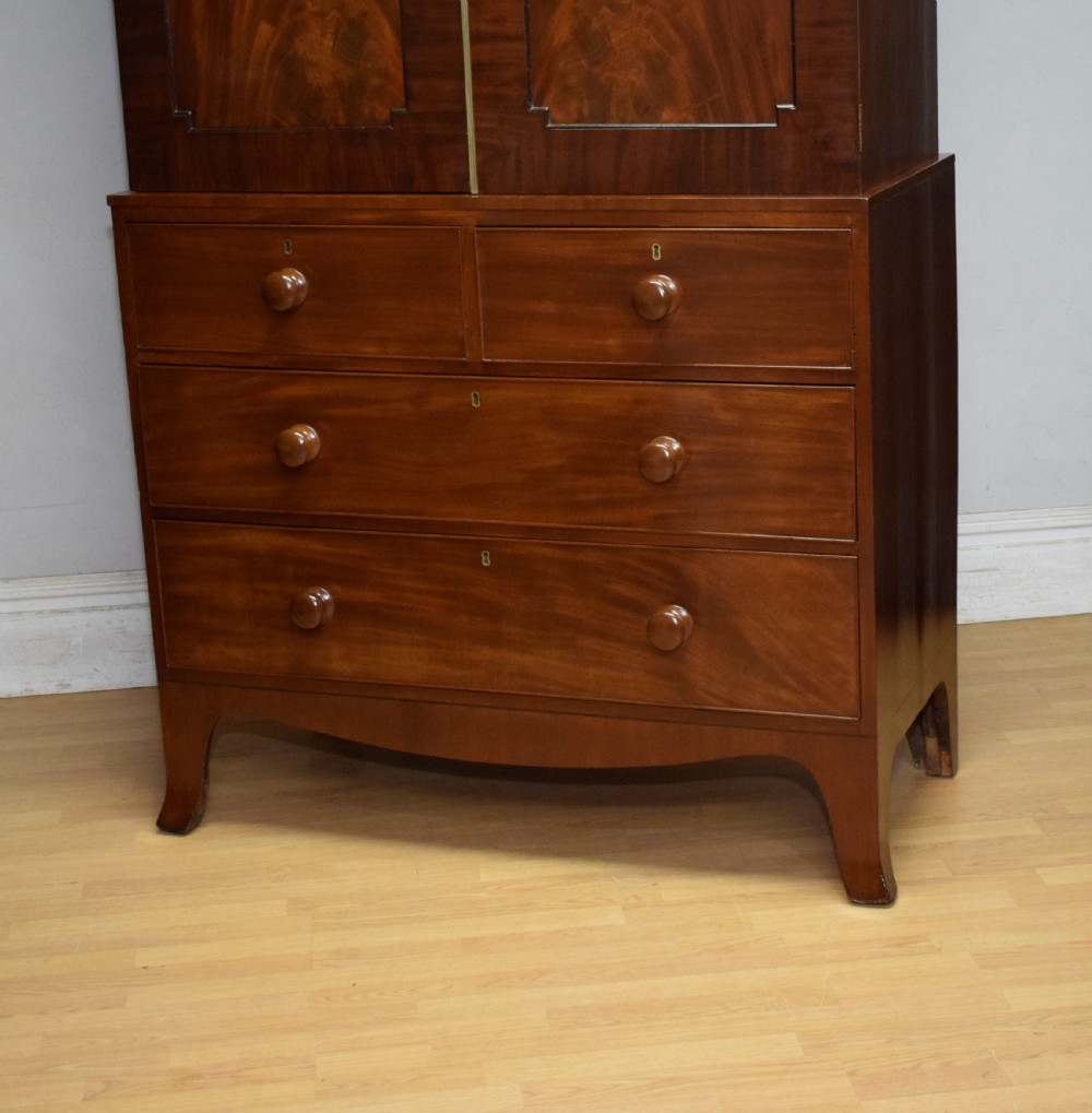 A Regency flame mahogany linen press featuring an arched pediment, twin cupboard doors above four drawers, and splayed bracket feet. View VII