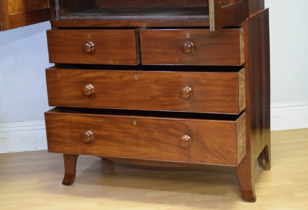 A Regency flame mahogany linen press featuring an arched pediment, twin cupboard doors above four drawers, and splayed bracket feet. View IX