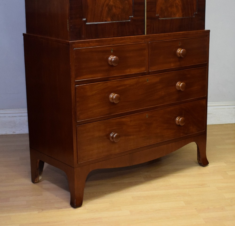 A Regency flame mahogany linen press featuring an arched pediment, twin cupboard doors above four drawers, and splayed bracket feet. View XV