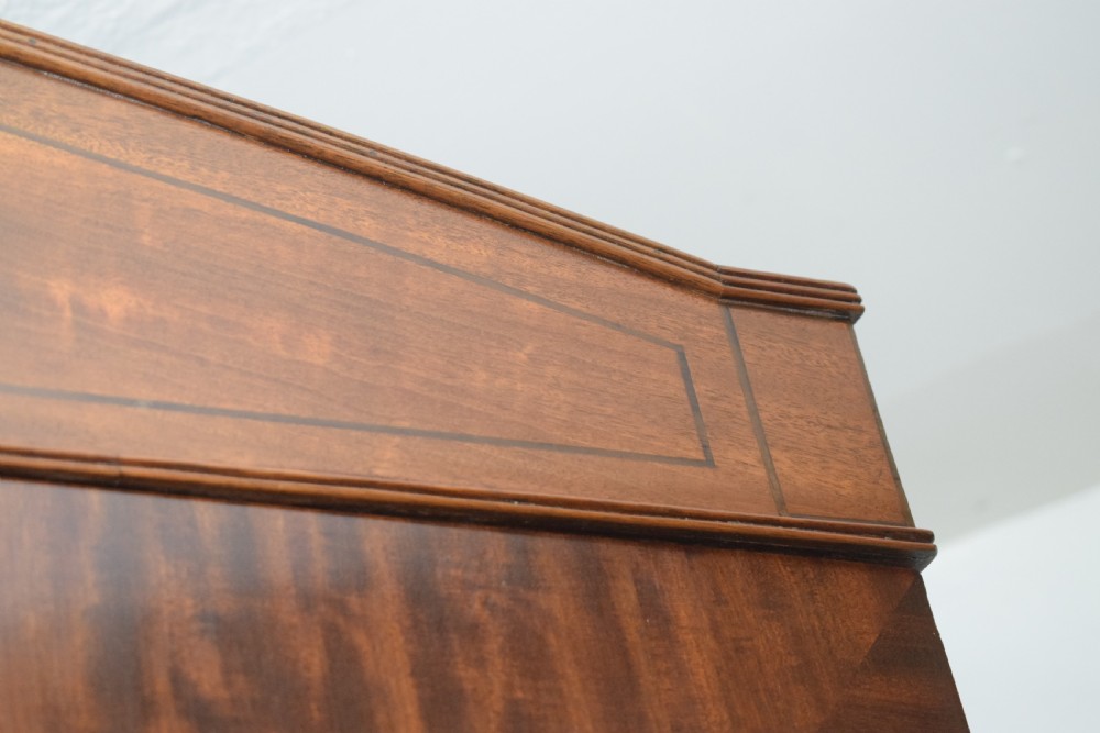 A Regency flame mahogany linen press featuring an arched pediment, twin cupboard doors above four drawers, and splayed bracket feet. View XIX