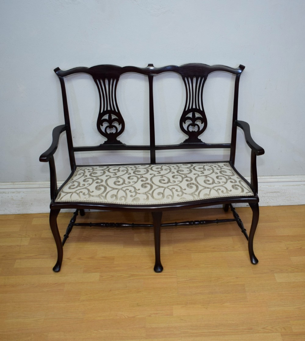 A late Victorian dark mahogany double chair-back settee featuring pierced splats, curved arms, cabriole front legs, and a patterned fabric seat. View II