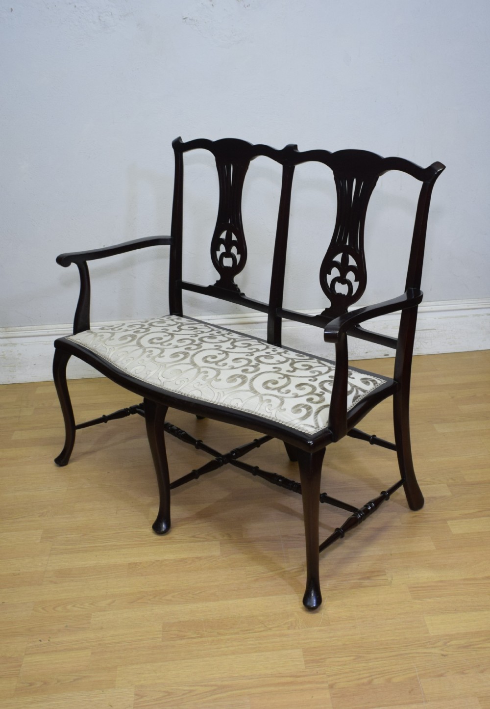 A late Victorian dark mahogany double chair-back settee featuring pierced splats, curved arms, cabriole front legs, and a patterned fabric seat. View VII