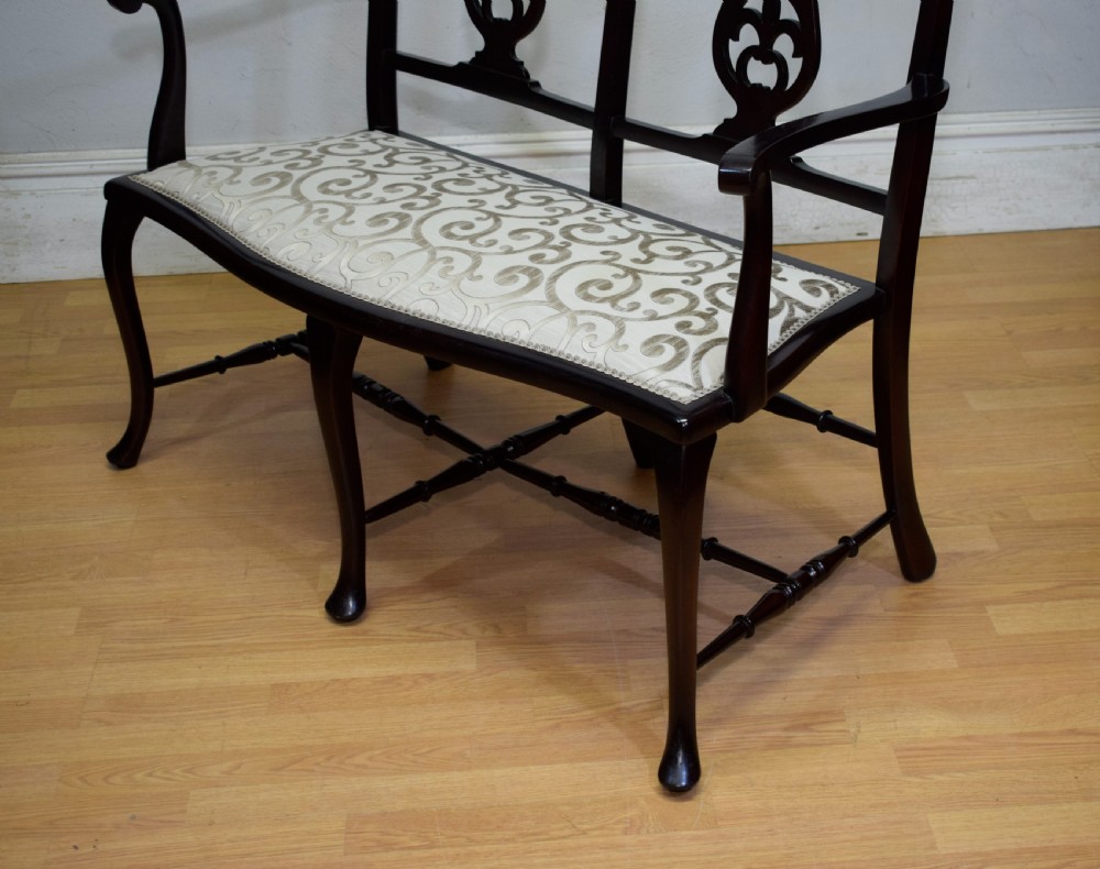 A late Victorian dark mahogany double chair-back settee featuring pierced splats, curved arms, cabriole front legs, and a patterned fabric seat. View VIII