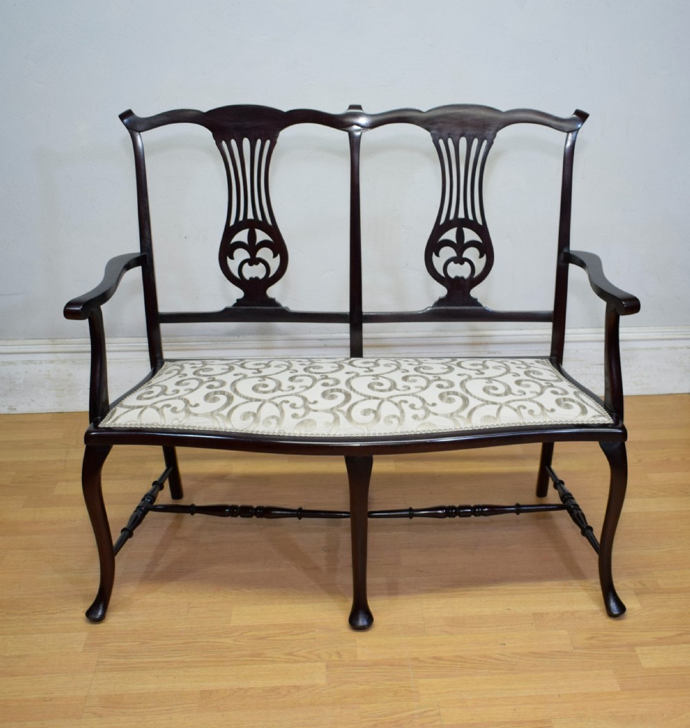 A late Victorian dark mahogany double chair-back settee featuring pierced splats, curved arms, cabriole front legs, and a patterned fabric seat. View XI